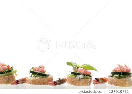 Minimalistic canapes with shrimps, salad and cucumber on a white background Minimalistic canapes with shrimps, salad and cucumber on a white background 127910781