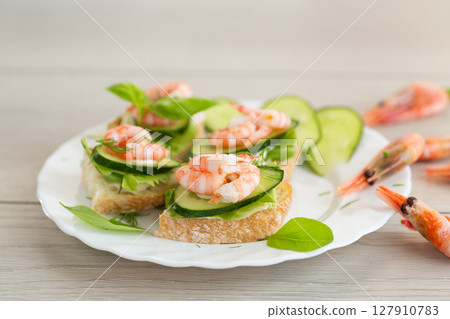 Mini canapes with shrimps, lettuce and cucumber, on a wooden table Mini canapes with shrimps, lettuce and cucumber, on a wooden table 127910783