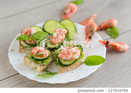 Portioned appetizers with shrimps, lettuce and sauce on a wooden table 127910784