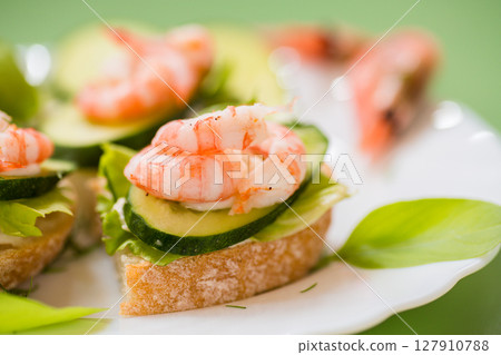 Portioned appetizers with shrimps, lettuce and sauce isolated on a green background 127910788
