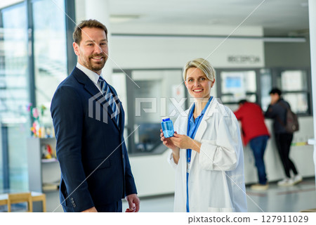 Doctor and pharmaceutical representative talking about new drug, clinical setting. 127911029