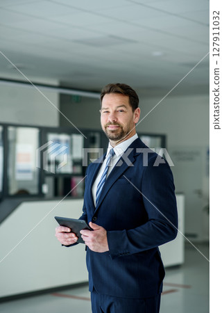 Business professional standing with tablet in hand, ready for presentation 127911032