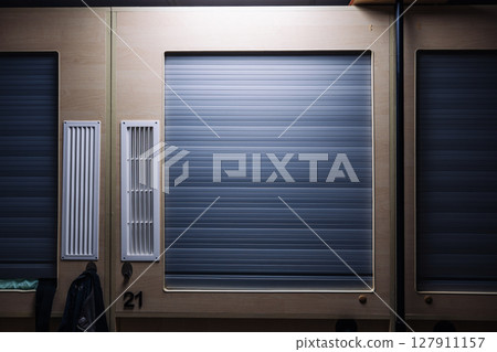 Capsule hotel room door closing, providing privacy and rest for travelers 127911157