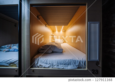 Capsule hotel room number twenty-three featuring comfortable bed, blanket and pillow 127911168