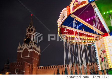 Colorful illuminated carousel spinning in front of the Moscow Kremlin at night 127911178