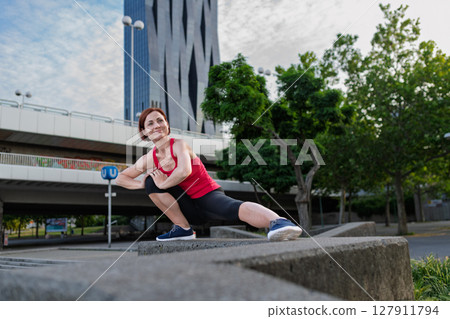 Woman working out in the city, doing bodyweight strength exercises outdoors 127911794