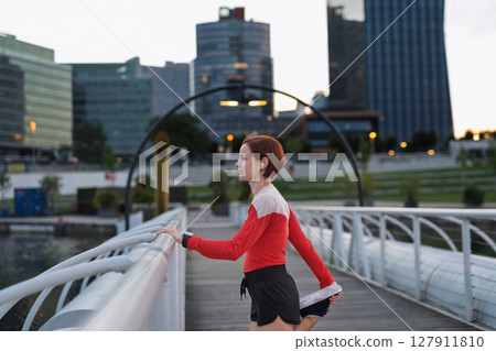 Sporty woman runner preparing for morning training, stretching. 127911810