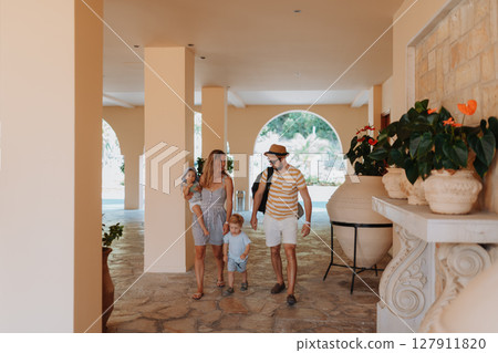 Young family walking through tropical hotel lobby Young family walking through tropical hotel lobby 127911820
