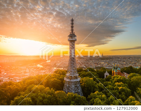 At sunrise, the Petrin Lookout Tower in Prague rises above a lush park, bathed in golden light, offering breathtaking views of the city and the surrounding landscape. 127912000