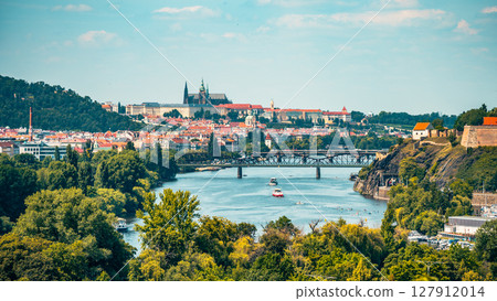 This panoramic view showcases the beauty of Prague, featuring the iconic Prague Castle and the Vltava River. Lush greenery and boats add to the charm of this historical cityscape. This panoramic view showcases the beauty of Prague, featuring the iconic Prague Castle and the Vltava River. Lush greenery and boats add to the charm of this historical cityscape. 127912014