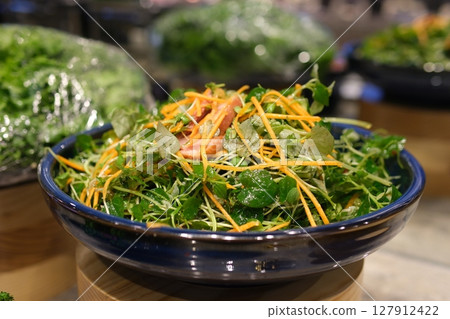 Put delicious fresh salad on the white plate. Healthy tasty salad with spinach, strawberry, avocado, nuts. Serving process. 127912422
