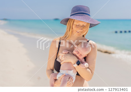Mother holding her newborn baby by the turquoise sea, sharing a peaceful and loving moment. Family bonding, motherhood, and travel with baby concept Mother holding her newborn baby by the turquoise sea, sharing a peaceful and loving moment. Family bonding, motherhood, and travel with baby concept 127913401