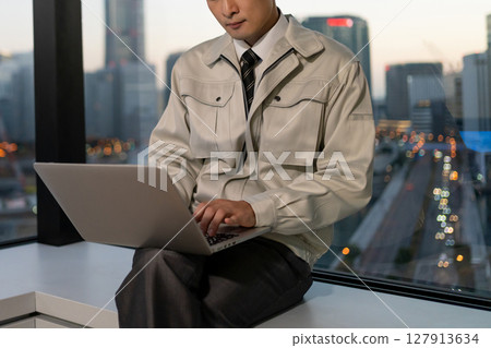 A man in work clothes operating a computer in an office A man in work clothes operating a computer in an office 127913634