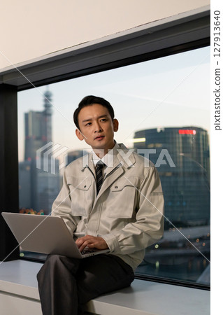 一名身穿工作服的男子在辦公室操作電腦 127913640