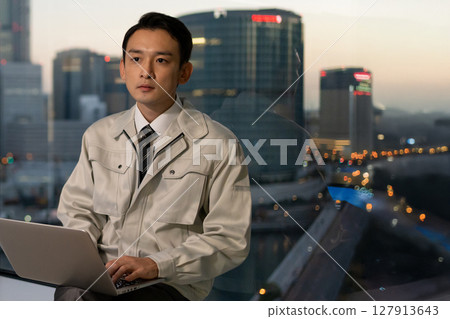 A man in work clothes operating a computer in an office A man in work clothes operating a computer in an office 127913643