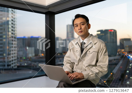 一名身穿工作服的男子在建築工地操作電腦 127913647