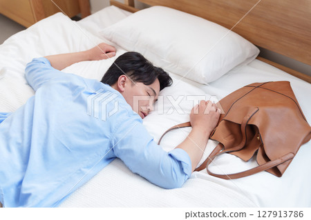 A man collapses into bed due to overwork 127913786