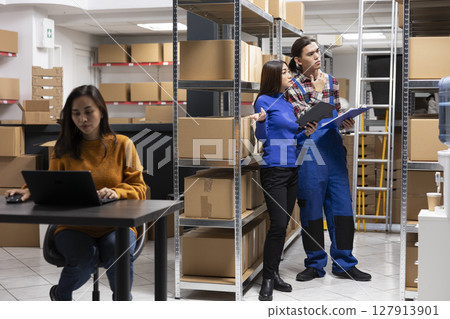 Asian team of workers in a depot checking the packages for shipment logistics, overseeing express delivery for orders. Staff focusing on growing the local brand small business. 127913901