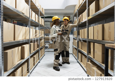 Multiethnic workers team tracking inventory using bar code systems, handling delivery crates for the order shipment. Factory workspace supports product storage and transportation logistics. Multiethnic workers team tracking inventory using bar code systems, handling delivery crates for the order shipment. Factory workspace supports product storage and transportation logistics. 127913920