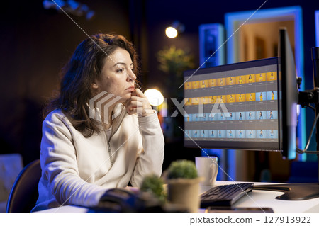 Photo editor retouching photographs with editing software on desktop computer, browsing through photoshoot stills to find images that need correcting. Photographer in home office adjusting images 127913922