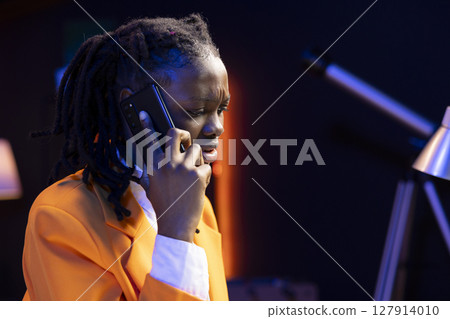 Girl squinting eyes, trying to understand school homework on laptop, doing telephone call to friend asking for assistance. Student struggling to understand class material, calling mate for help 127914010