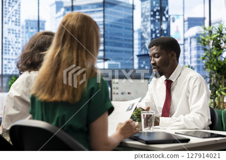 HR professionals negotiating job offers and salary packages with candidate after successful conversation. HR coworkers talking with applicant, analyzing resume, cover letter and background information HR professionals negotiating job offers and salary packages with candidate after successful conversation. HR coworkers talking with applicant, analyzing resume, cover letter and background information 127914021