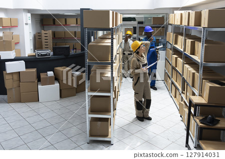 Female worker in a storage depot handles packages supply chain, managing inventory systems, focusing on storage organization and delivery services in a highly structured logistics center. 127914031