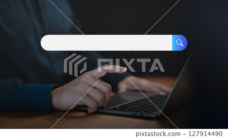 Adult man using a laptop searching on the internet. SEO technology networking, representing online browsing, information seeking, and digital search technology in a modern workspace. 127914490