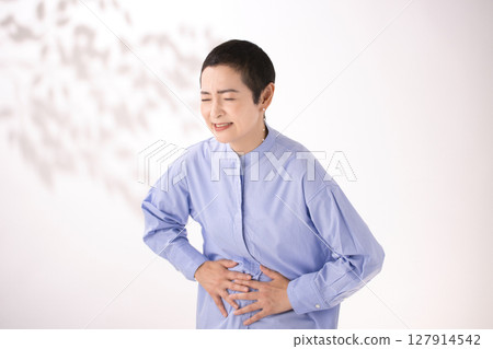 Middle-aged woman grimacing with stomach pain 127914542