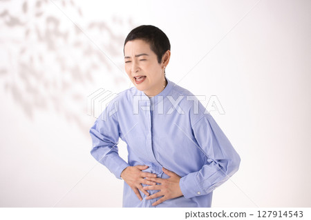 Middle-aged woman grimacing with stomach pain Middle-aged woman grimacing with stomach pain 127914543