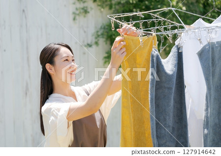 A woman hanging up the laundry A woman hanging up the laundry 127914642