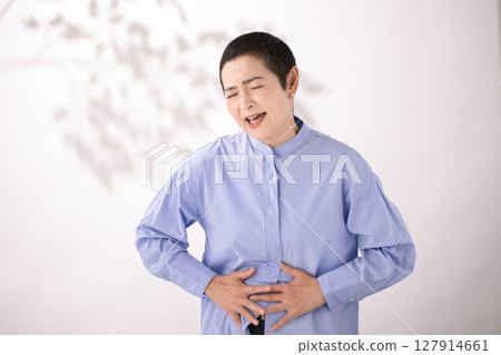 Middle-aged woman grimacing with stomach pain 127914661
