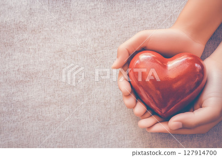 Hands Holding Red Heart Symbolizing Love, Care, and Affection on Soft Background Surface 127914700