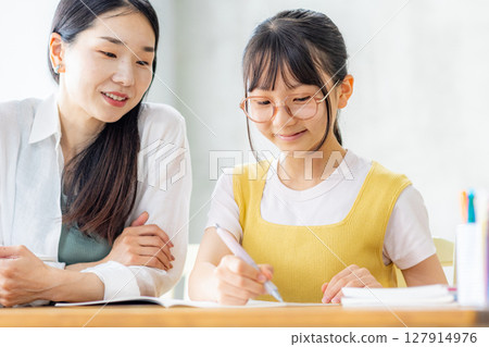 小學生在學習，他的母親在教他 127914976