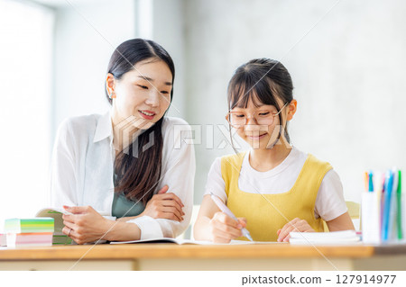 Elementary school student studying and his mother teaching him 127914977
