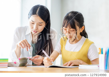 小學生在學習，他的母親在教他 127914990