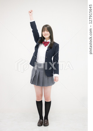 Full body of a high school girl jumping with a fist pump, looking at the camera 127915645