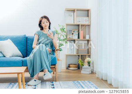 一名中年婦女在客廳裡看著智能手機 一名中年婦女在客廳裡看著智能手機 127915855