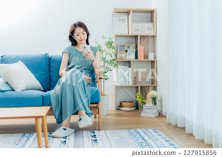 A middle-aged woman watching a smartphone in the living room A middle-aged woman watching a smartphone in the living room 127915856
