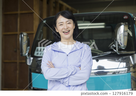 Middle-aged woman standing in front of a truck Middle-aged woman standing in front of a truck 127916179