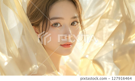 一位美麗的年輕女子的美麗形象與柔軟的金色面紗般的面料 127916464