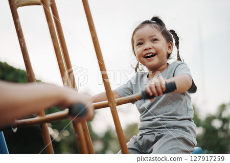 cheerful toddler girl playing on double swing with freind at outdoor playground 127917259