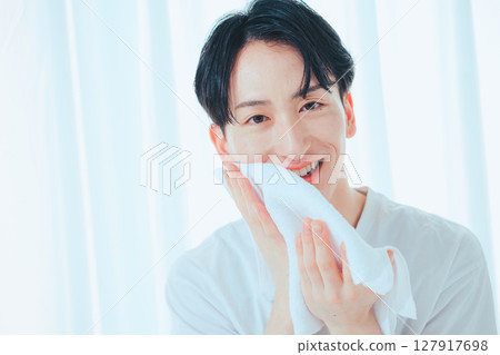 A clean-cut man in his 20s washing his face and taking care of his skin 127917698