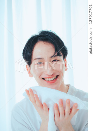 A clean-cut man in his 20s washing his face and taking care of his skin 127917701