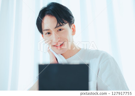 A refreshing man using a towel in front of the mirror after washing his face in the morning 127917755