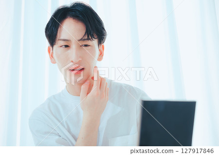 A refreshing guy checking his skin in the mirror — Men's skin care habits 127917846
