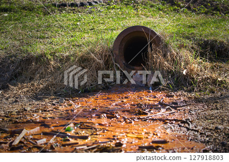 Rusty Drain Pipe Releasing Polluted Water Into Contaminated Soil in a Rural Outdoor Environment Rusty Drain Pipe Releasing Polluted Water Into Contaminated Soil in a Rural Outdoor Environment 127918803