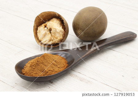 Monk fruit on a white board and Monk fruit extract powder in a spoon Monk fruit on a white board and Monk fruit extract powder in a spoon 127919053