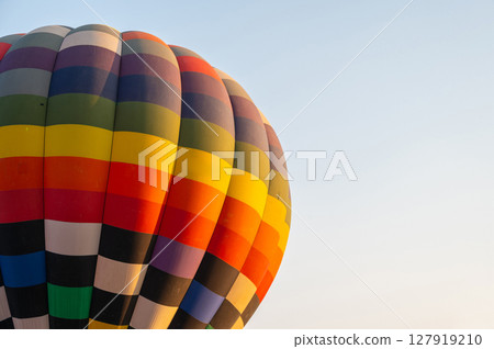 Cropped shot view of hot air balloon envelope against the sky. The envelope is the part of the hot air balloon that is full of hot air and it makes it rise. Cropped shot view of hot air balloon envelope against the sky. The envelope is the part of the hot air balloon that is full of hot air and it makes it rise. 127919210