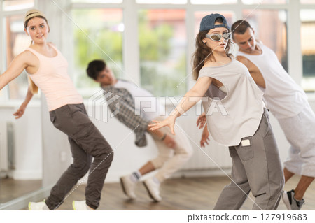 Young girl standing performs basic hip hop movements in front of group of students Young girl standing performs basic hip hop movements in front of group of students 127919683